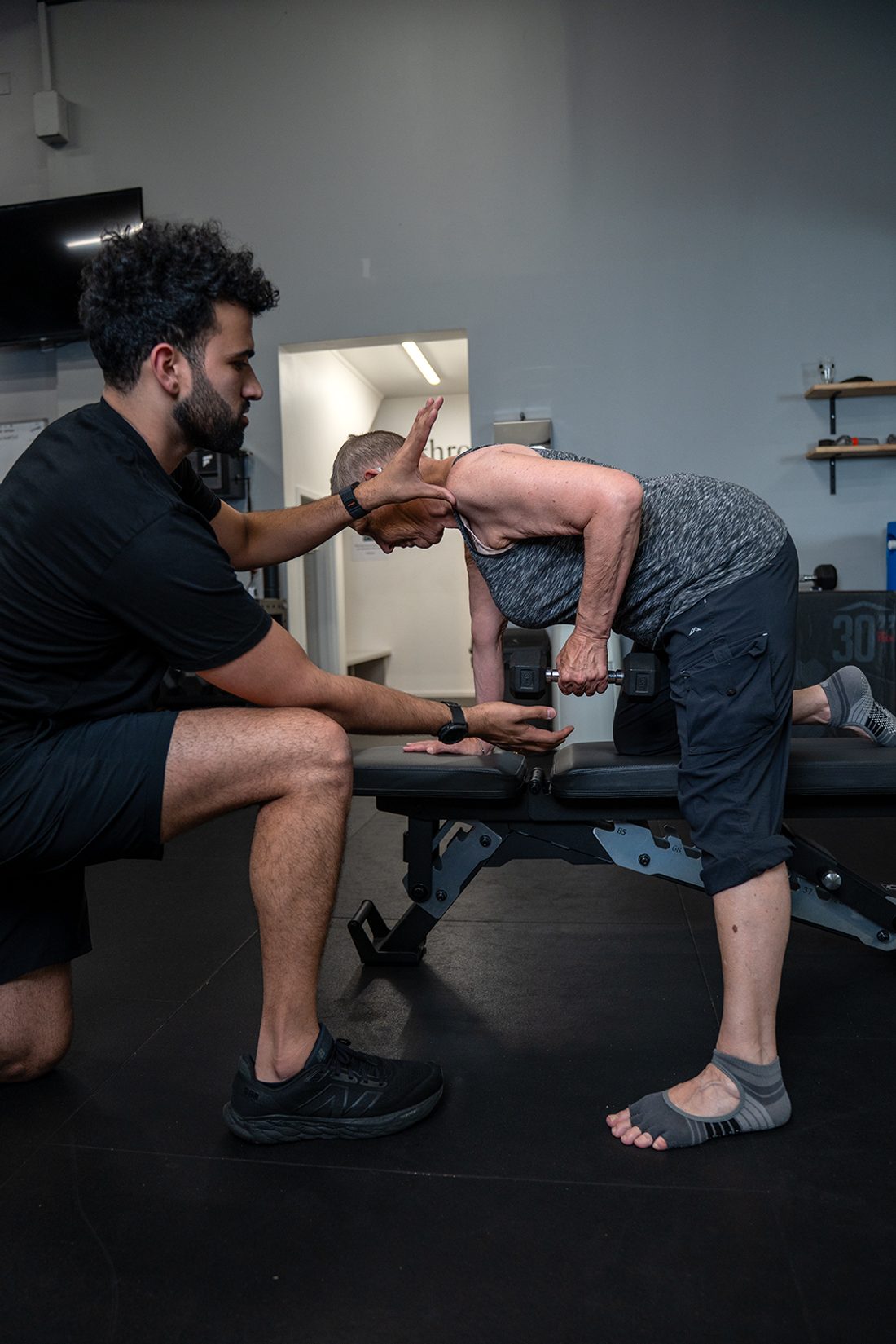 Exercise physiologist guiding an older adult through strength training in Auckland